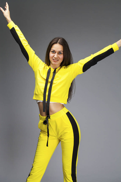 Portrait of a young beautiful brunette woman in yellow tracksuit - Foto, imagen