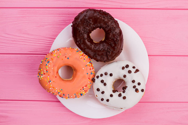 Three donuts on plate, top view. - Фото, изображение