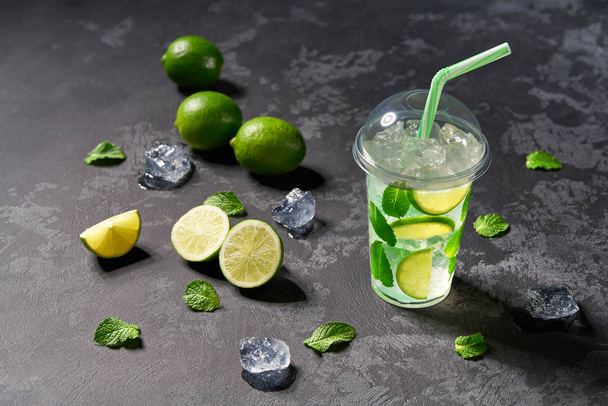 frischer Mojito-Cocktail in einer durchsichtigen Plastikschale mit Limettenscheiben, - Foto, Bild