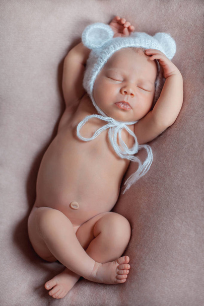 Niña recién nacida de diez días vistiendo sombrero de oso blanco de ganchillo duerme pacíficamente en manta rosa
. - Foto, imagen