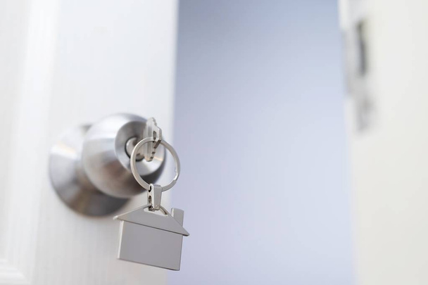 klíč k domu ve tvaru klíčenky stříbrný klíček v odemykacího vchodu otevřených dveří. koncepce nákupu nemovitostí a bytu. - Fotografie, Obrázek