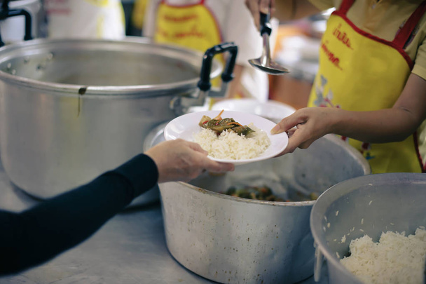 De handen van de armen krijgen voedsel uit de handen van de filantroop: concept van geven - Foto, afbeelding