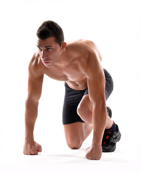 Healthy and fitness man on running start position on white background. - Foto, imagen