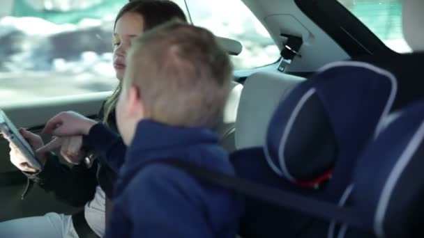młodszy brat i siostra kłócą tablet pc podczas jazdy rodzinne wakacje - Materiał filmowy, wideo