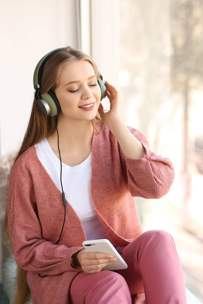 Belle jeune femme qui écoute de la musique à la maison - Photo, image