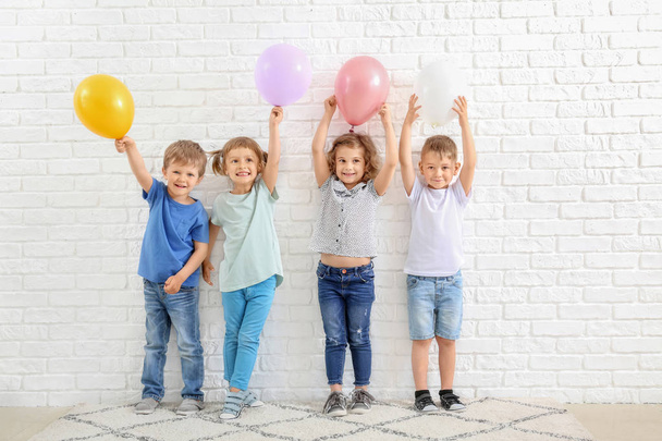 Cute little children with air balloons near white brick wall - Fotoğraf, Görsel