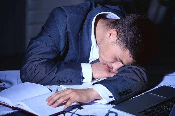 Hombre de negocios cansado durmiendo en la mesa de la oficina tarde en la noche
 - Foto, Imagen