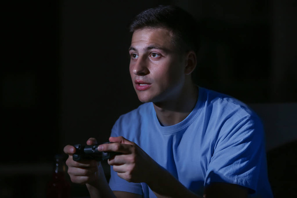 Jeune homme jouant à un jeu vidéo tard dans la soirée
 - Photo, image