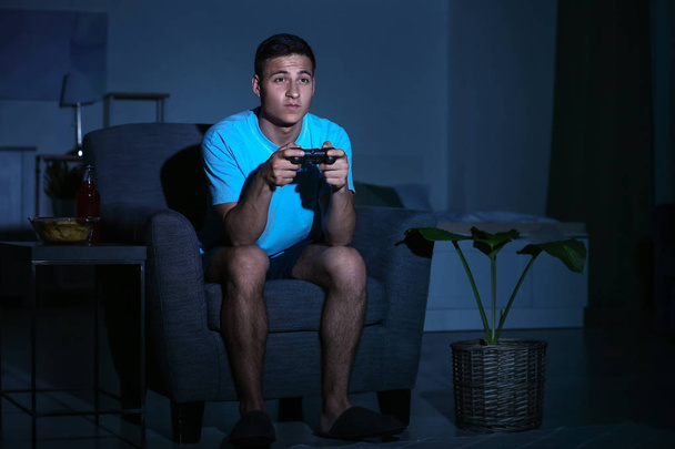 Jeune homme jouant à un jeu vidéo tard dans la soirée
 - Photo, image