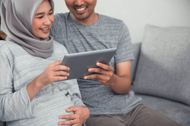 Schwangere benutzt Tablet-PC mit Ehemann - Foto, Bild