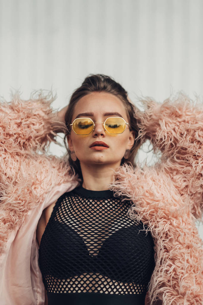 Close Up Portrait of One Stylish Girl in Pink Coat and Modern Yellow Sunglasses Posing on Street - Fotoğraf, Görsel