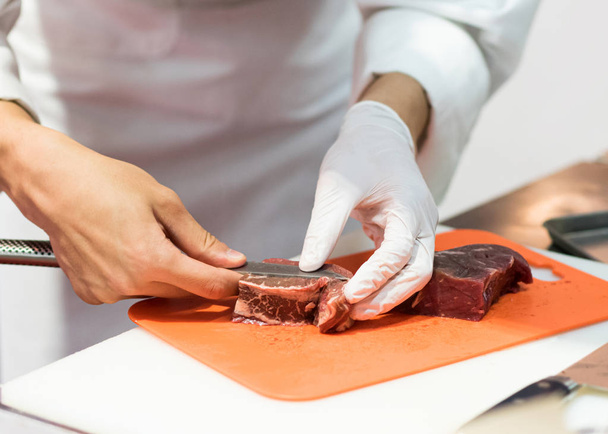 Chef cutting fresh raw meat with knife in the kitchen, Chef cutt - Photo, Image