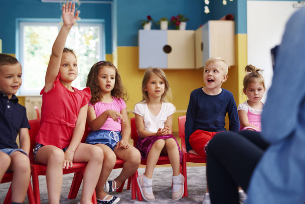 Дівчина піднімає руку, щоб поставити запитання в класі
 - Фото, зображення