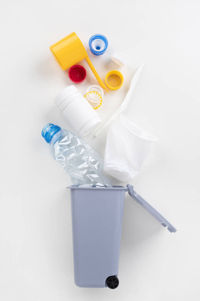 Trash bin with plastic waste on a gray background. Recycling concept - 写真・画像