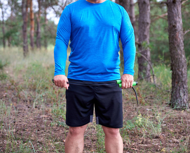 homem adulto em roupas azuis segurando uma corda de salto para praticar esportes
 - Foto, Imagem