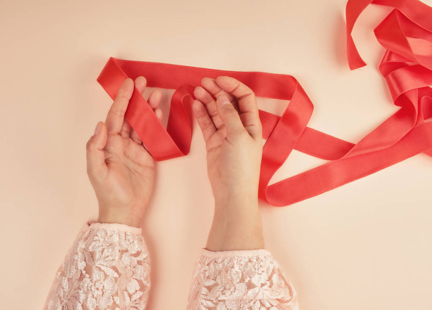 two female hands and red silk ribbon - Φωτογραφία, εικόνα