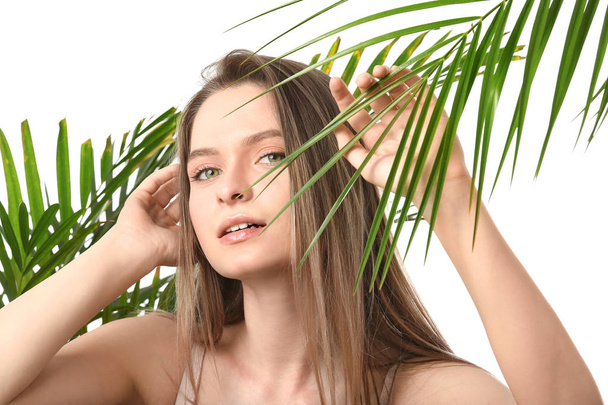 白い背景に熱帯の葉を持つ美しい若い女性 - 写真・画像
