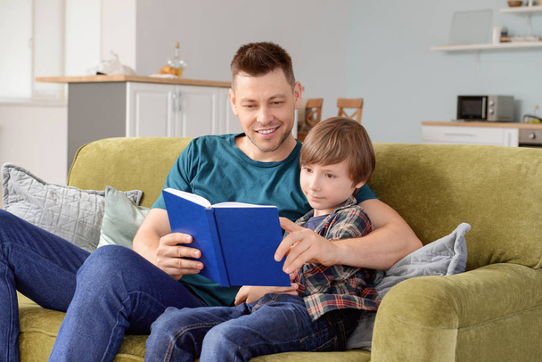 Father and his little son reading book at home - Photo, Image