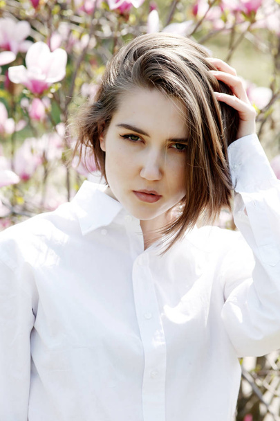 Young beautiful model woman posing in the garden of blooming magnolias. - Foto, imagen