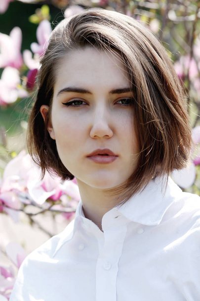 Young beautiful model woman posing in the garden of blooming magnolias. - Fotografie, Obrázek
