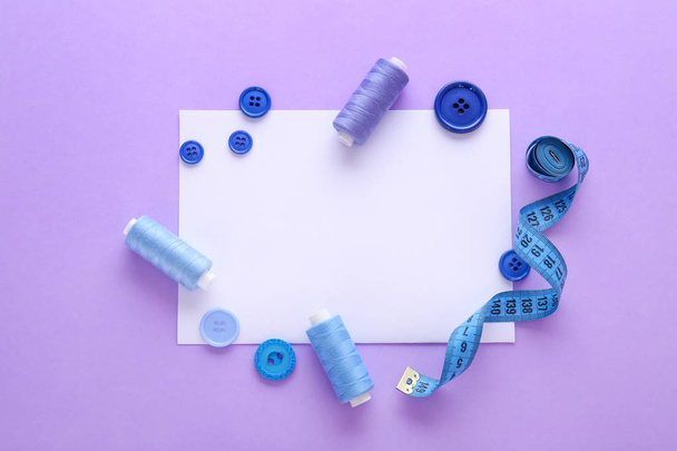 Набор нитей для шитья с аксессуарами и листом бумаги на цветном фоне
 - Фото, изображение