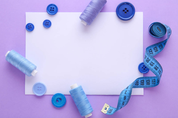 Conjunto de hilos de coser con accesorios y hoja de papel sobre fondo de color
 - Foto, Imagen