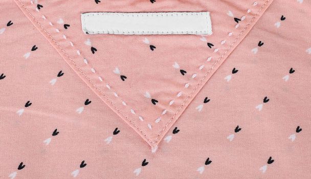 Close-up van blanco kleding label op roze textiel achtergrond. lege kleren label mockup - Foto, afbeelding