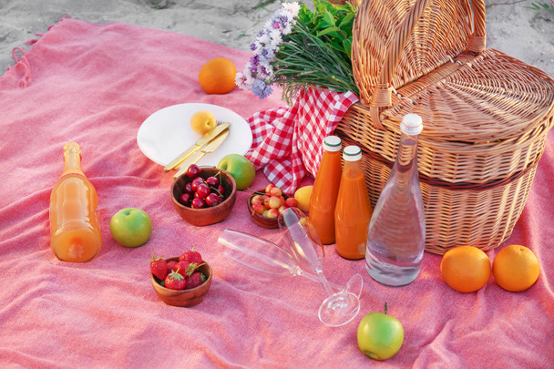 Wicker basket with tasty food and drink for romantic picnic on beach - Photo, Image