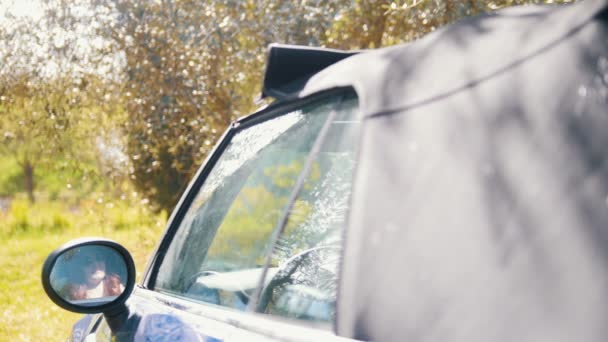 Het dak van de cabriolet opent, een jonge vrouw kan worden gezien in de achteruitkijkspiegel - Video