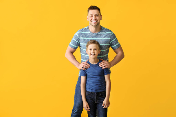 Happy man with little adopted boy on color background - Foto, afbeelding