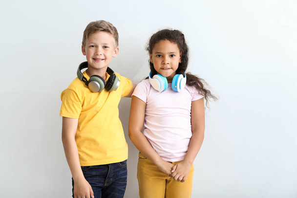 Cute little children with headphones on light background - Photo, image