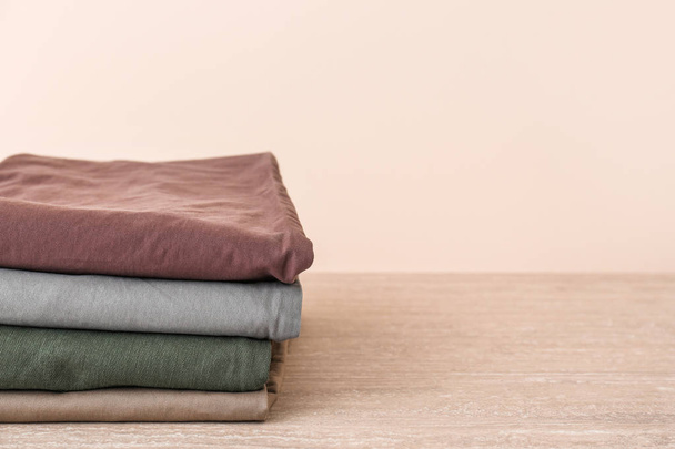 Stack of clean clothes on table against light background - Fotoğraf, Görsel