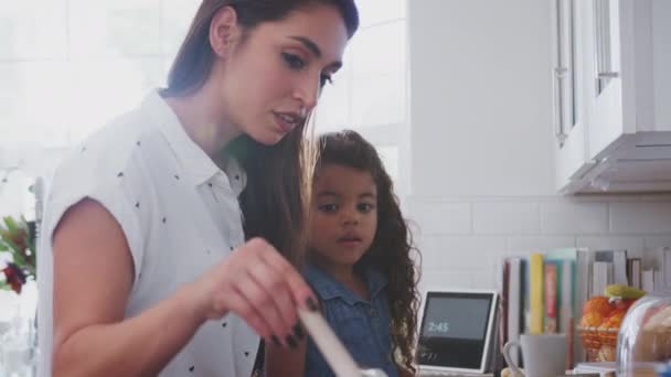 Ισπανίδα γυναίκα και νεαρή κόρη που μαγειρεύουν μαζί στην εστία στην κουζίνα, κοντινό, πλευρική όψη - Πλάνα, βίντεο