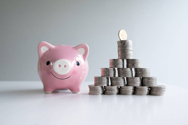 munt en roze Piggy Bank met munten piramide, groei van bedrijf naar succes en besparing voor pensioen concept - Foto, afbeelding