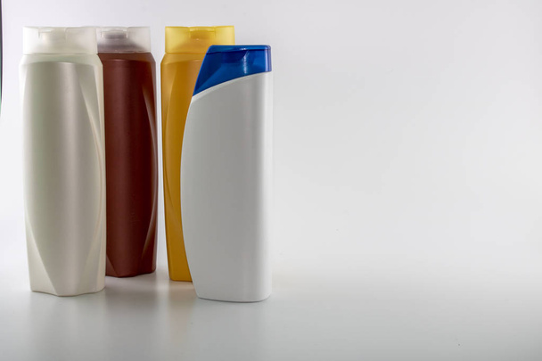 Şampuan, kahverengi, beyaz, sarı renklerde nemlendirici şişeler. Beyaz arka planda çekim. Ortasında mavi kapak ile - Fotoğraf, Görsel