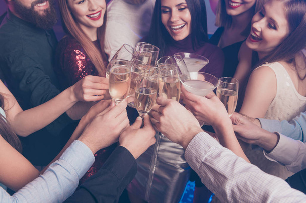 Cropped close-up view of nice lovely adorable glamorous fascinating attractive gorgeous cheerful glad ladies and guys having fun clinking wineglasses sparkles feast at fogged lights nightclub - Фото, изображение