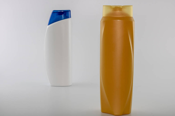Shampoo hydraterende flessen in bruin; wit gele kleuren. Fotograferen in witte achtergrond. Met blauwe dop in het midden - Foto, afbeelding