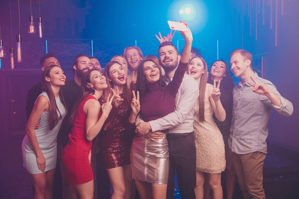 Portrait of nice well-dressed chic glamorous attractive shine stylish cheerful cheery positive glad excited ladies and guys having fun taking selfie showing v-sign at luxury fogged nightclub indoors - Photo, Image