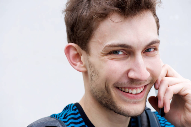 Close up portrait of happy young man talking with cellphone by white background - Photo, Image