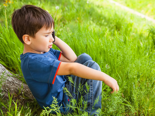 boy in green grass talking on cell phone - Foto, imagen