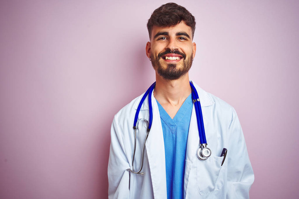 Young doctor man with tattoo wearing stethocope standing over isolated pink background with a happy and cool smile on face. Lucky person. - Photo, Image