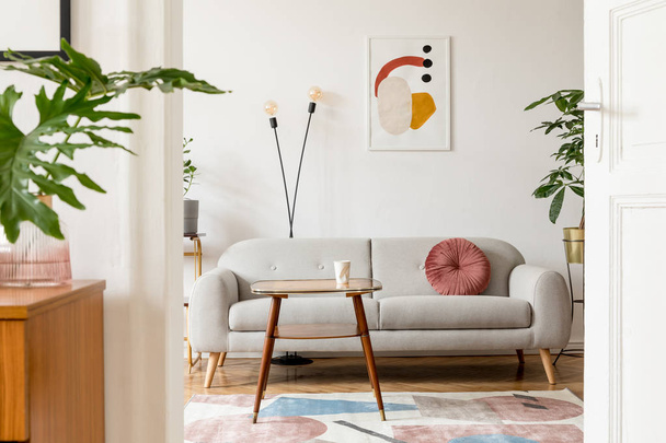 Stylish retro interior of living room with design commode, vinyl recorder, tropical leaf and mock up posters frames on the white walls. Cozy room with brown wooden parquet and plants. - Φωτογραφία, εικόνα