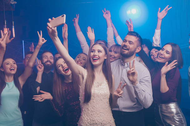 Portrait of nice chic glamorous attractive fashionable stylish gorgeous cheerful positive glad funny ladies and guys having fun making selfie showing v-sign symbol at modern fogged lights nightclub - Foto, afbeelding