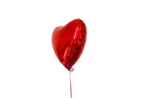 boule gonflable en forme de coeur rouge, avec une corde sur fond blanc, isoler. le concept de vacances, d'anniversaire et d'amour
. - Photo, image