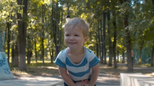 Nieśmiały i uśmiechnięty chłopiec dziecka. Dzieciak w parku - Materiał filmowy, wideo