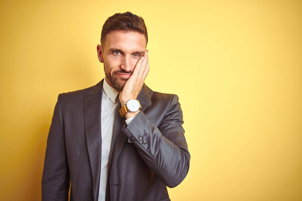 Young handsome business man over yellow isolated background thinking looking tired and bored with depression problems with crossed arms. - Foto, imagen