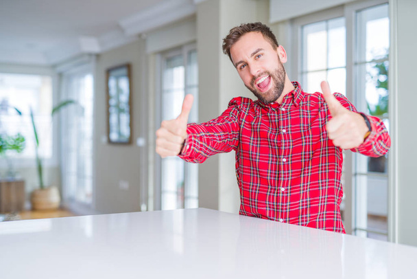 Handsome man wearing colorful shirt approving doing positive gesture with hand, thumbs up smiling and happy for success. Looking at the camera, winner gesture. - Fotografie, Obrázek