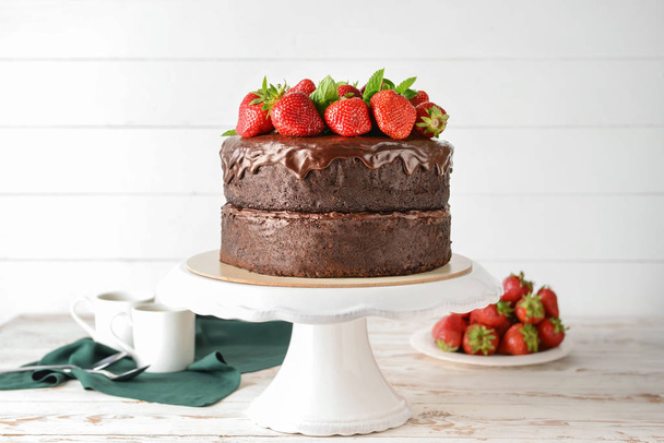 Stand con gustosa torta al cioccolato su tavolo di legno bianco
 - Foto, immagini