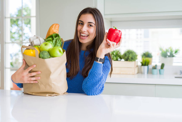 Fiatal gyönyörű nő mosolyogva kezében papír táska tele fűszeres - Fotó, kép