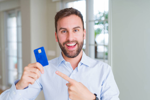 Komea liikemies jolla luottokortti erittäin onnellinen osoittaa käsin ja sormella
 - Valokuva, kuva